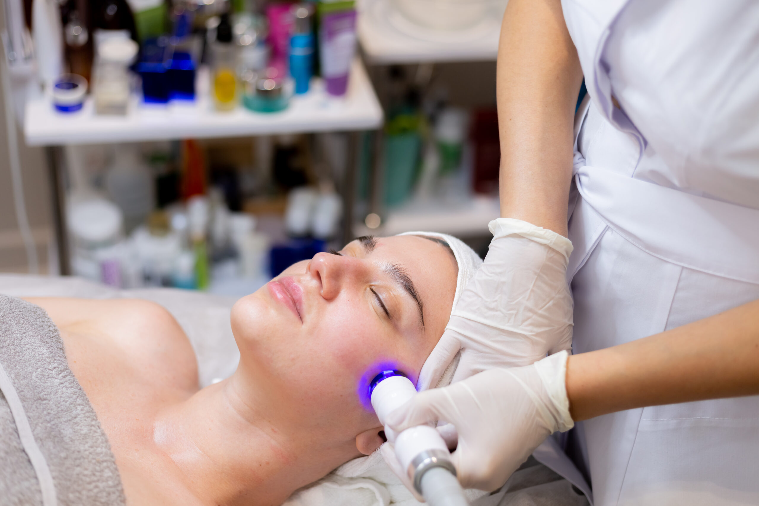 Person lying calmly in a full-body SpectraLight therapy bed at Light Therapy San Diego studio, soft blue and red glowing lights visible around them
